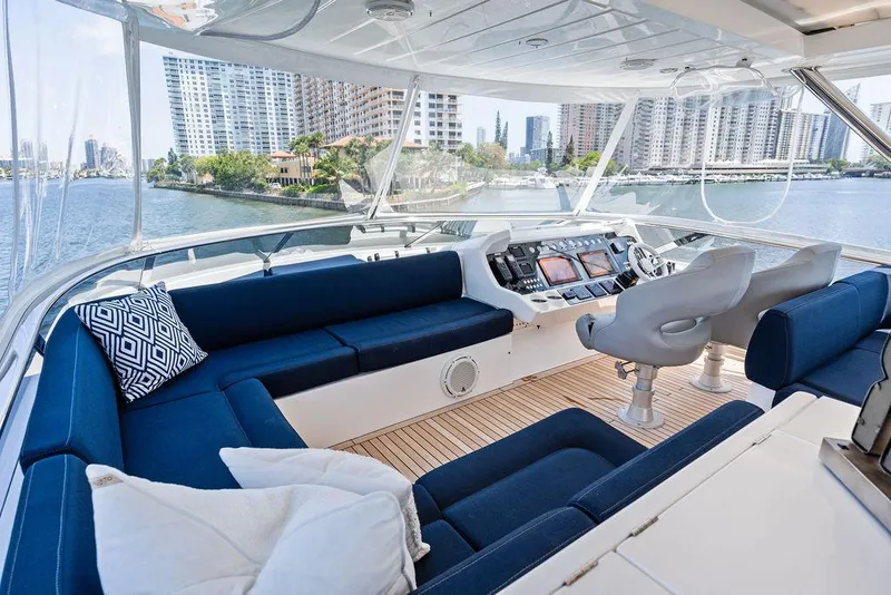 Slide: The Image of Luxurious 2019 Sunseeker 86 Yacht interior with blue seating and modern helm, overlooking waterfront cityscape. - 33
