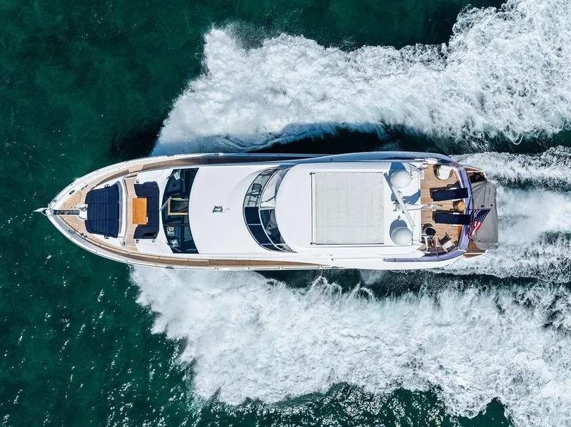 Slide: The Image of 2019 Sunseeker 86 Yacht cruising on blue ocean with city skyline in background. - 7
