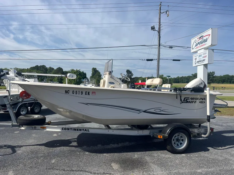 Slide: The Image of 2017 Carolina Skiff 178 DLV boat on trailer, parked outdoors near dealership sign. - 0