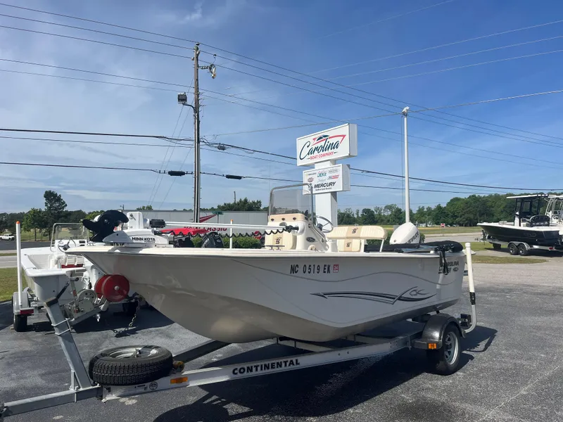 Slide: The Image of 2017 Carolina Skiff 178 DLV boat on trailer, parked outdoors under clear blue sky. - 1