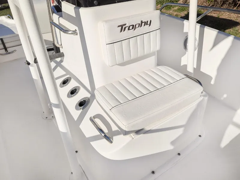 Slide: The Image of 2024 Bayliner Trophy T18 boat interior with white seating and "Trophy" logo. - 10