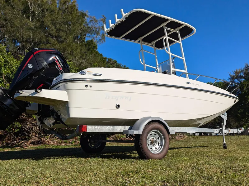 Slide: The Image of 2024 Bayliner Trophy T18 boat on trailer, side view, outdoors on grass. - 3