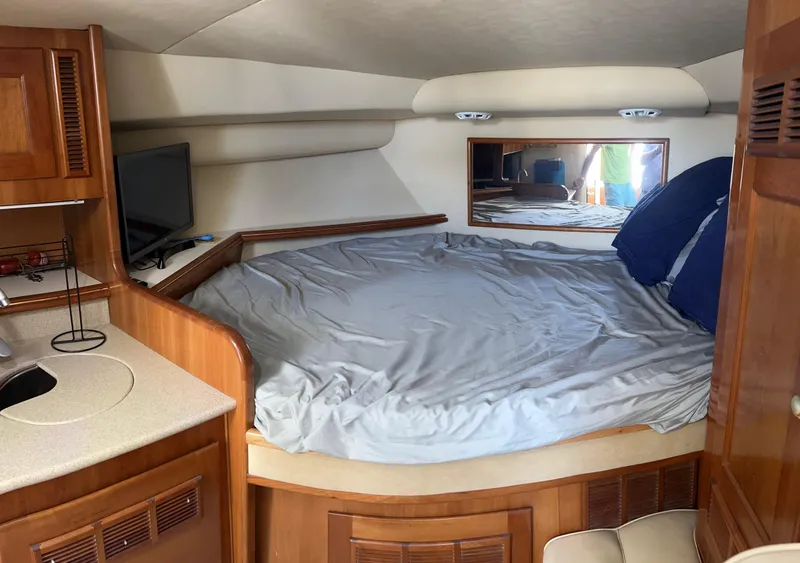 Slide: The Image of 2005 Rampage 30' Express Sportfish cabin with bed, TV, and wooden cabinetry. - 43