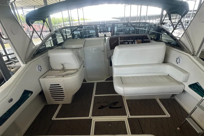Slide: The Image of 1994 Sea Ray 370 Express Cruiser interior with white seating and helm, docked in marina. - 16