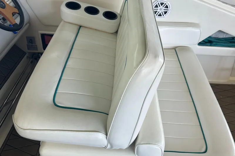 Slide: The Image of 1994 Sea Ray 370 Express Cruiser interior with white cushioned seating and cup holders. - 20