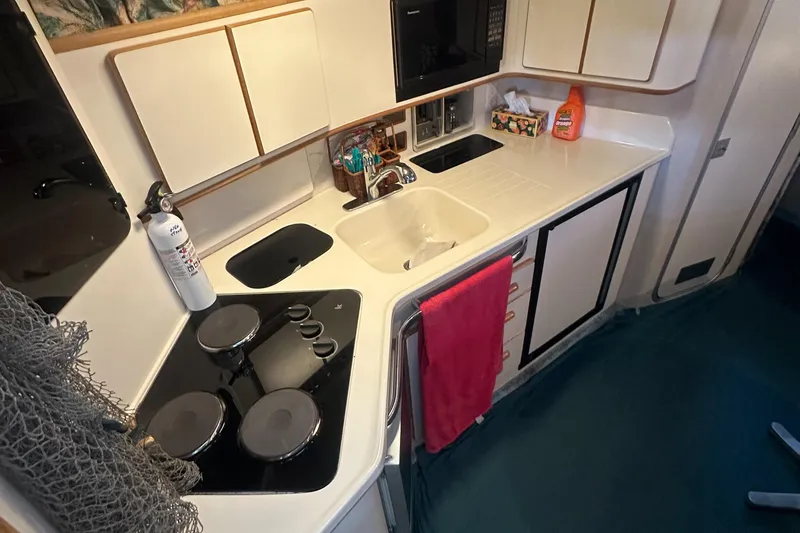 Slide: The Image of 1994 Sea Ray 370 Express Cruiser kitchen with stove, sink, and storage cabinets. - 32