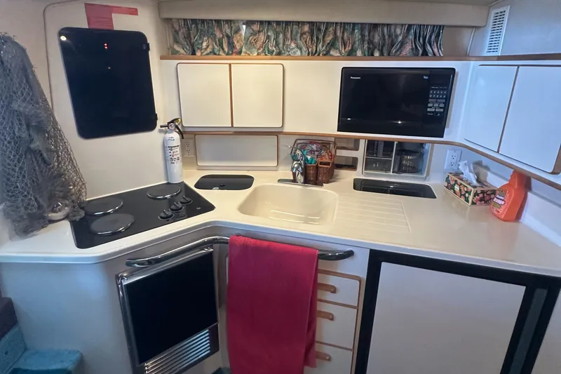 Slide: The Image of 1994 Sea Ray 370 Express Cruiser kitchen with stove, sink, microwave, and storage cabinets. - 35