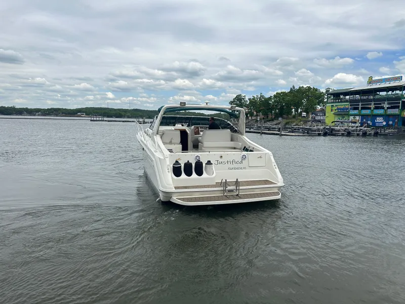 Slide: The Image of 1994 Sea Ray 370 Express Cruiser on a calm lake near a marina. - 4