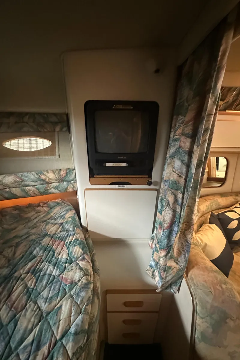 Slide: The Image of 1994 Sea Ray 370 Express Cruiser cabin interior with TV and patterned bedding. - 43