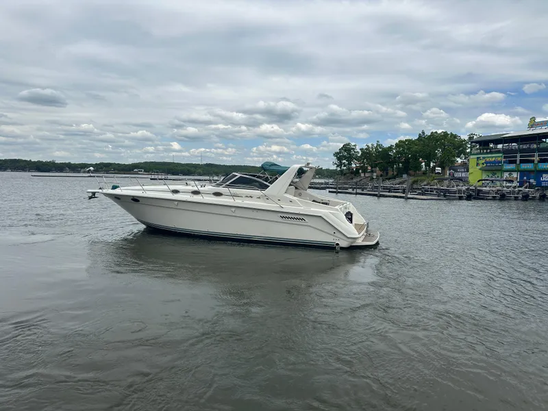 Slide: The Image of 1994 Sea Ray 370 Express Cruiser on calm water, overcast sky, dock in background. - 6