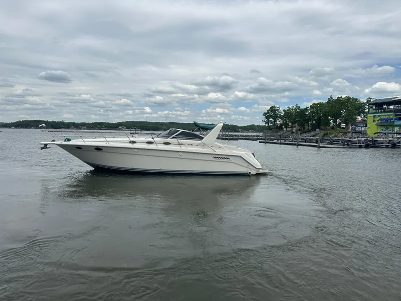 Slide: The Image of 1994 Sea Ray 370 Express Cruiser on calm water near a marina. - 7