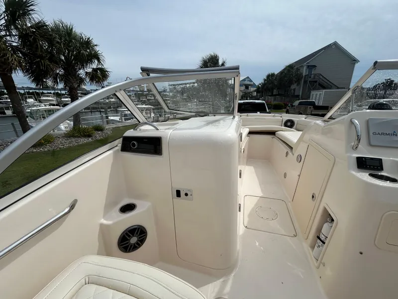 Slide: The Image of 2022 Grady-White Freedom 215 boat interior with seating and console, docked near palm trees. - 15