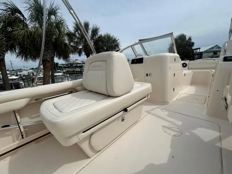 Slide: The Image of 2022 Grady-White Freedom 215 boat interior with white seating and palm trees in the background. - 6