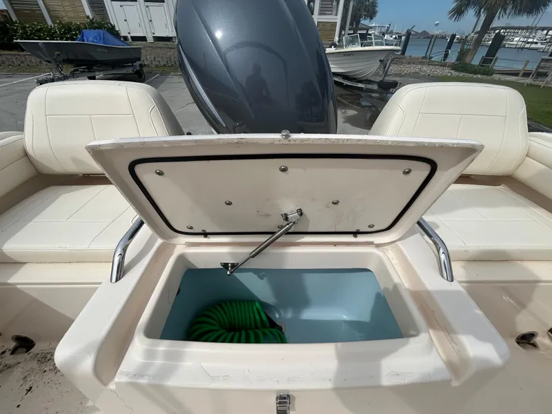 Slide: The Image of 2022 Grady-White Freedom 215 boat with open storage compartment and green hose. - 8