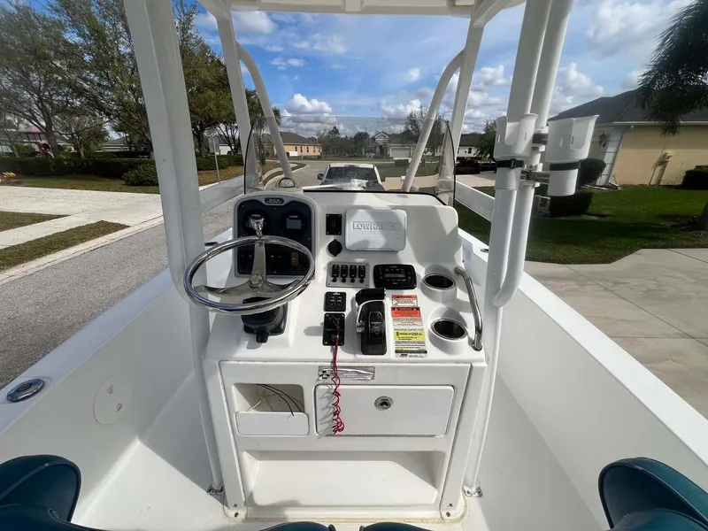 Slide: The Image of 2014 Sea Hunt SXS boat console with steering wheel and controls, parked in a residential area. - 6