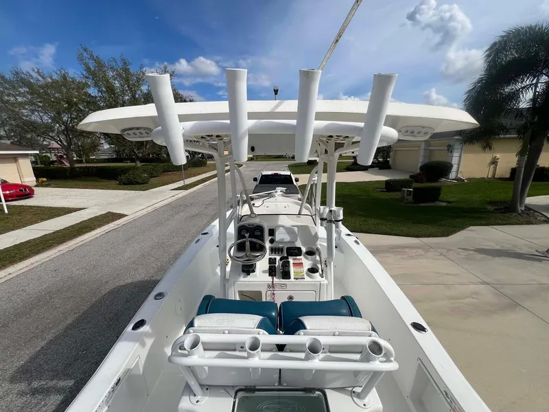 Slide: The Image of 2014 Sea Hunt SXS boat with rod holders, steering console, and seating, parked in a residential area. - 8