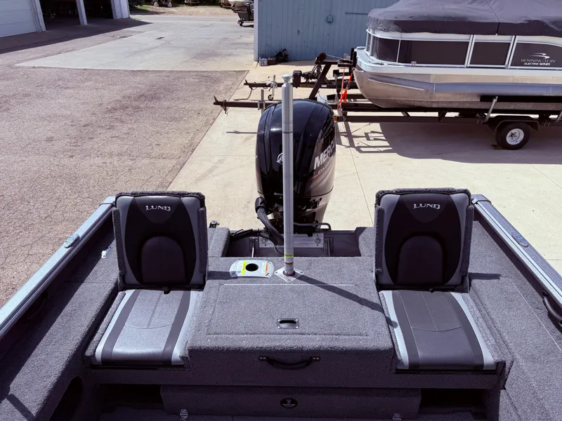 Slide: The Image of 2018 Lund 1675 Impact Sport boat interior with Mercury outboard motor, docked near a pontoon. - 25