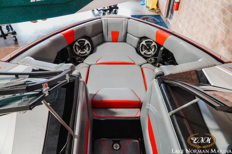 Slide: The Image of 2021 Malibu 23 LSV boat interior with gray and red seating, speakers, and cup holders. - 18