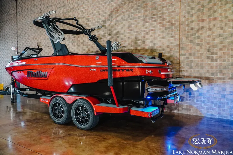 Slide: The Image of 2021 Malibu 23 LSV boat in vibrant red on a trailer indoors. - 3