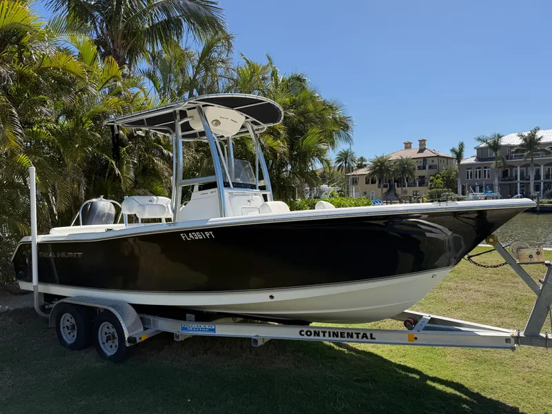 Slide: The Image of 2014 Sea Hunt Ultra 211 boat on trailer, surrounded by palm trees. - 0