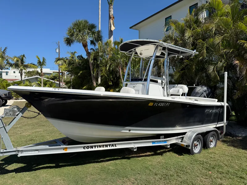 Slide: The Image of 2014 Sea Hunt Ultra 211 boat on trailer, parked on grass with palm trees in background. - 1