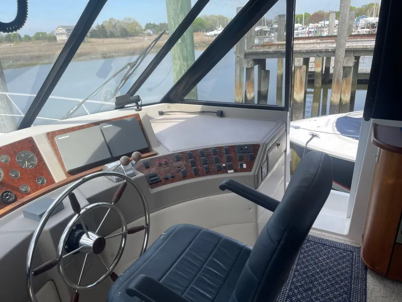 Slide: The Image of 1999 Bayliner 4788 Motoryacht helm with steering wheel, control panel, and waterfront view. - 10