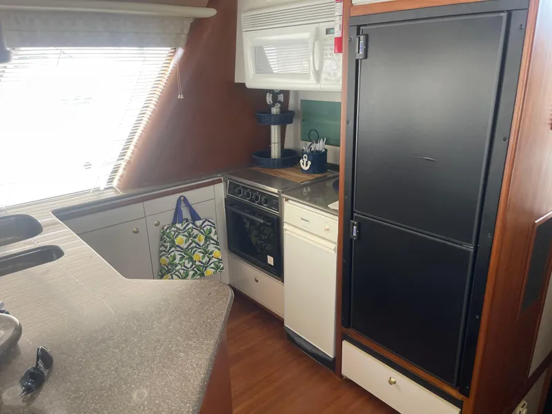 Slide: The Image of 1999 Bayliner 4788 Motoryacht kitchen with stove, fridge, and countertop. - 19