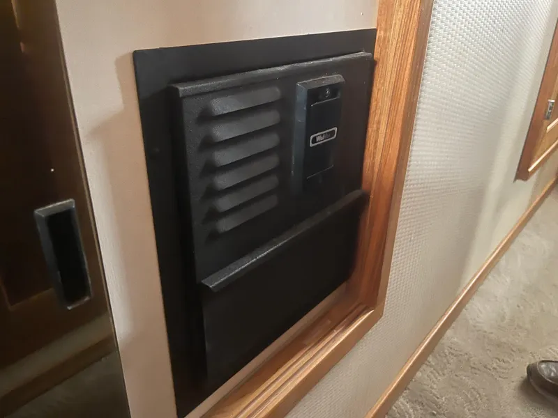 Slide: The Image of Wall-mounted vent panel inside 1999 Bayliner 4788 Motoryacht, featuring wood trim and textured wall. - 23