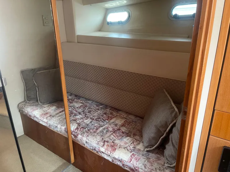 Slide: The Image of 1999 Bayliner 4788 Motoryacht interior cabin with cushioned seating and porthole windows. - 25