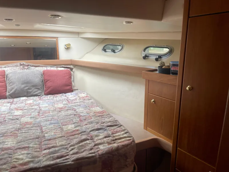 Slide: The Image of Cozy bedroom interior of 1999 Bayliner 4788 Motoryacht with bed, pillows, and wooden cabinetry. - 28