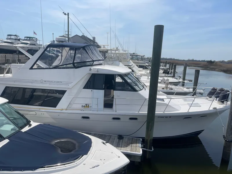Slide: The Image of 1999 Bayliner 4788 Motoryacht docked at a marina under a clear blue sky. - 3