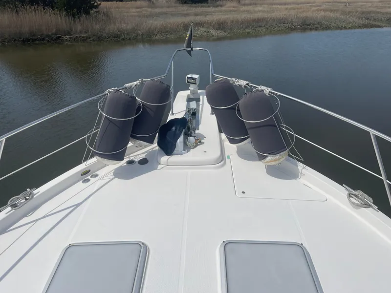 Slide: The Image of 1999 Bayliner 4788 Motoryacht bow view with fenders on calm water. - 4