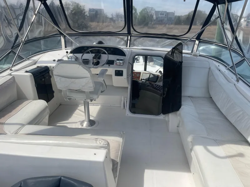 Slide: The Image of 1999 Bayliner 4788 Motoryacht cockpit with white seating and steering area. - 7