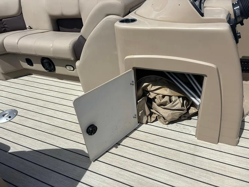 Slide: The Image of 2023 SunCatcher Fusion 22RC boat interior with open storage compartment and beige seating. - 17