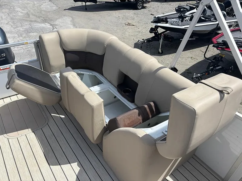 Slide: The Image of 2023 SunCatcher Fusion 22RC boat seating with storage compartments, beige upholstery, and cup holders. - 22