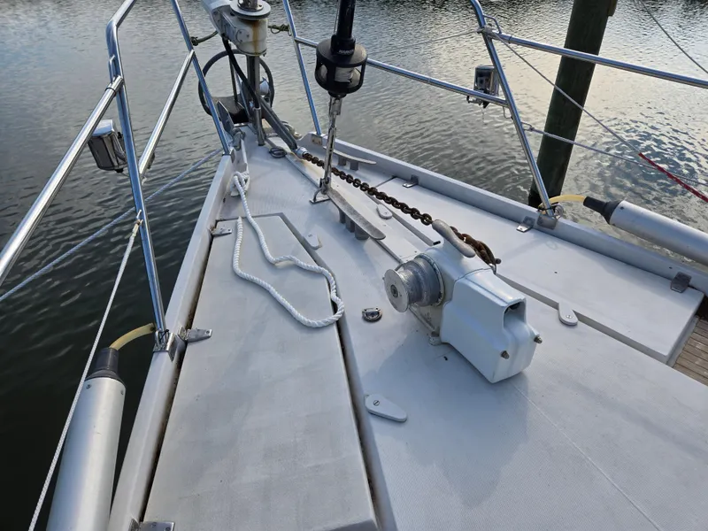 Slide: The Image of Deck of 1985 Amel Maramu sailboat with anchor chain and winch, docked by calm water. - 13