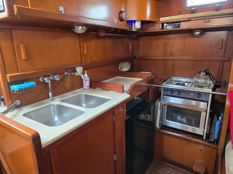 Slide: The Image of 1985 Amel Maramu yacht kitchen with dual sinks, stove, and wooden cabinetry. - 29