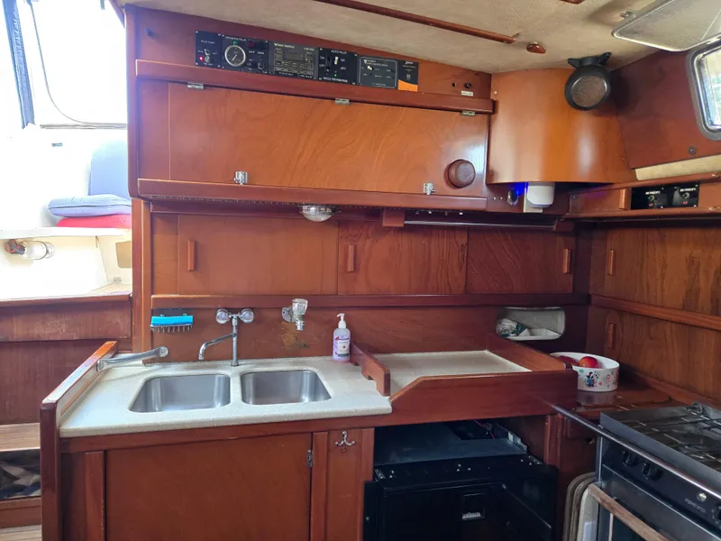 Slide: The Image of 1985 Amel Maramu yacht kitchen with wooden cabinets, double sink, and stove. - 30