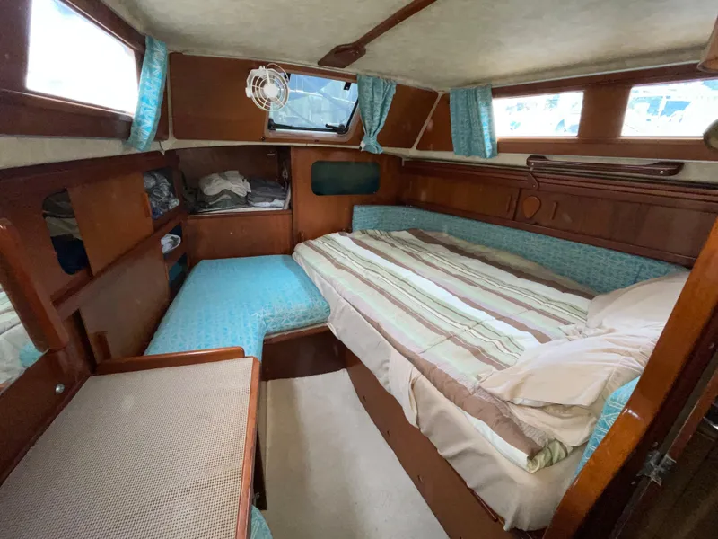 Slide: The Image of 1985 Amel Maramu yacht cabin with cozy bed, wooden interior, and blue accents. - 31