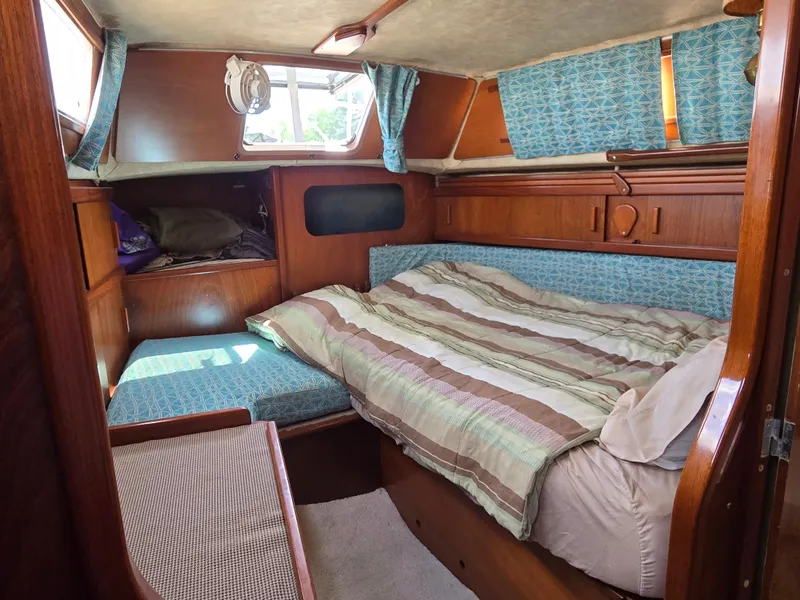 Slide: The Image of Cozy cabin interior of 1985 Amel Maramu sailboat with striped bedding and wooden furnishings. - 32