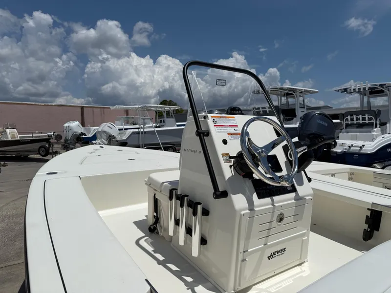 Slide: The Image of 2025 Hewes 18 Redfisher boat with steering console, docked under a cloudy sky. - 7