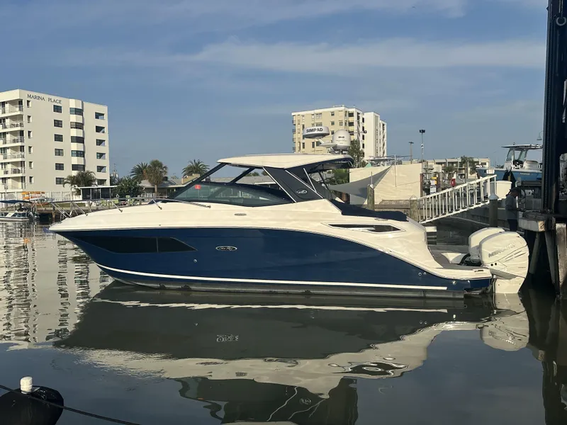 Slide: The Image of 2021 Sea Ray Sundancer 320 OB docked at marina, modern buildings in background. - 0