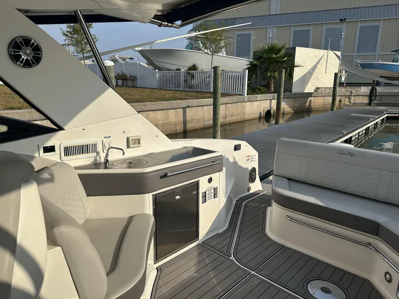 Slide: The Image of 2021 Sea Ray Sundancer 320 OB interior with seating, kitchenette, and dockside view. - 2