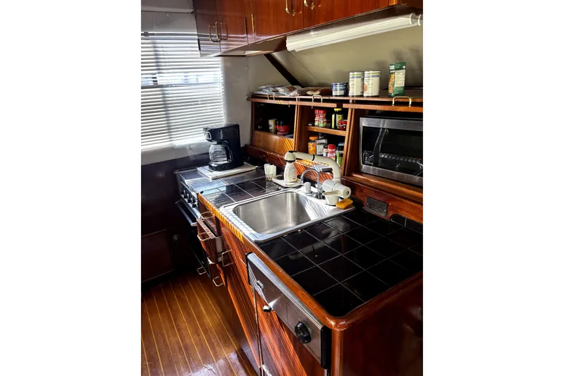 Slide: The Image of 1989 Ocean Yachts 55 Super Sport kitchen with wooden cabinets, black countertops, and modern appliances. - 24