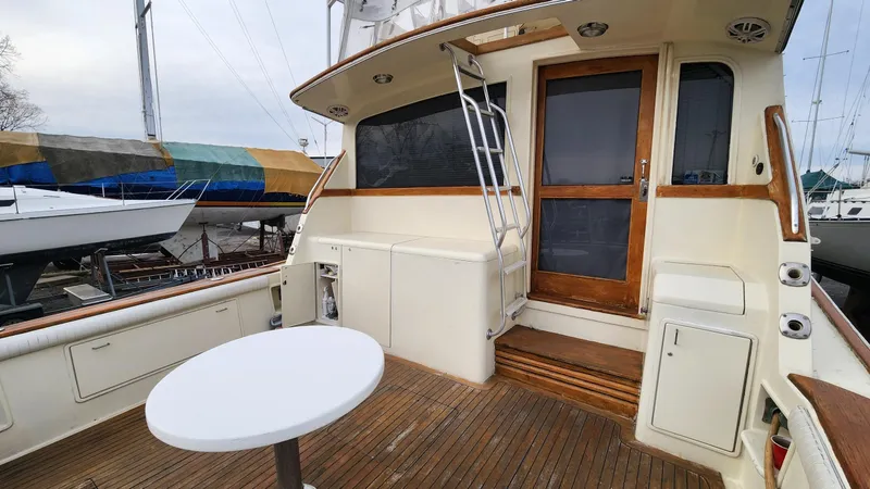 Slide: The Image of 1989 Ocean Yachts 55 deck with wooden flooring and round table, docked near other boats. - 3
