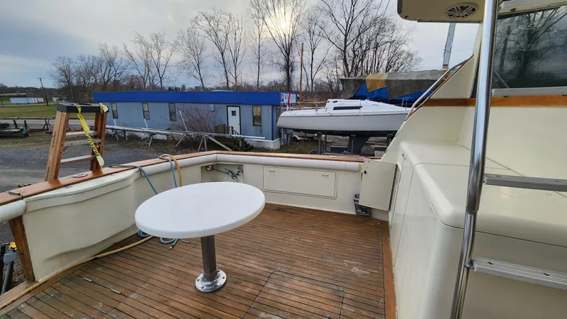 Slide: The Image of 1989 Ocean Yachts 55 deck with table, docked near blue building and trees. - 4