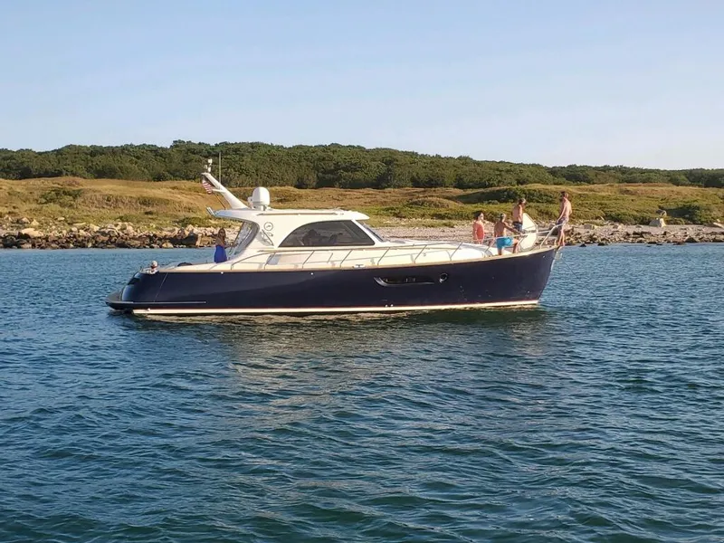 Slide: The Image of 2007 Mochi Craft 44 Dolphin yacht cruising on calm waters near a scenic coastline. - 0