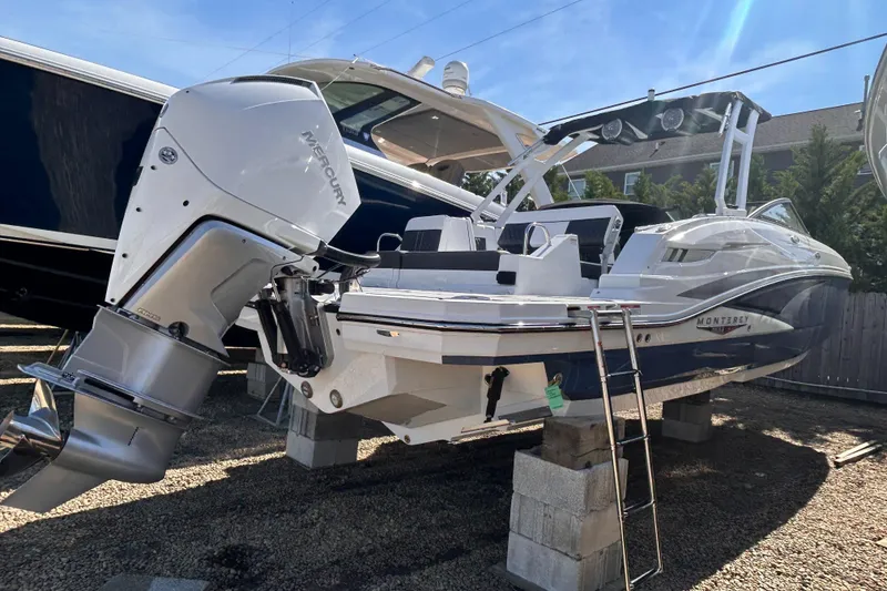 Slide: The Image of 2025 Monterey M65 boat with powerful outboard engine, displayed on blocks under clear blue sky. - 7