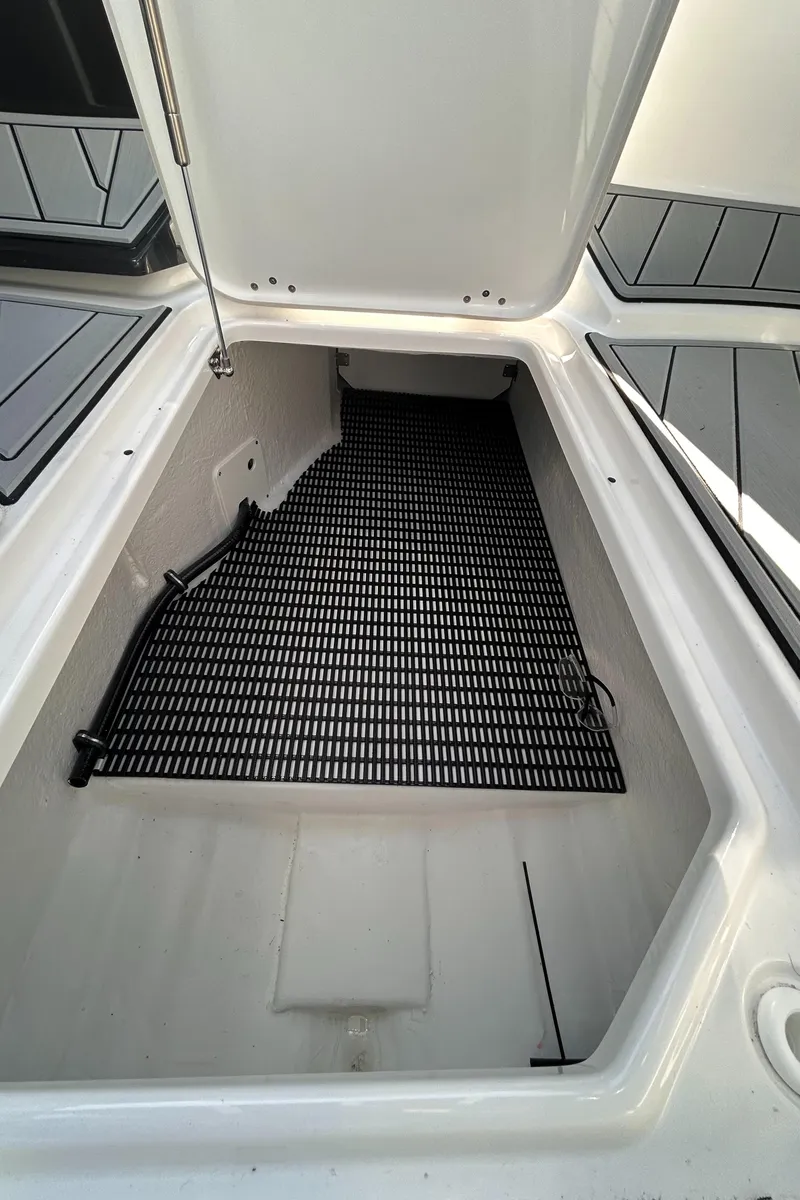 Slide: The Image of Open storage compartment in 2025 Monterey M65 boat, featuring a black non-slip mat. - 9