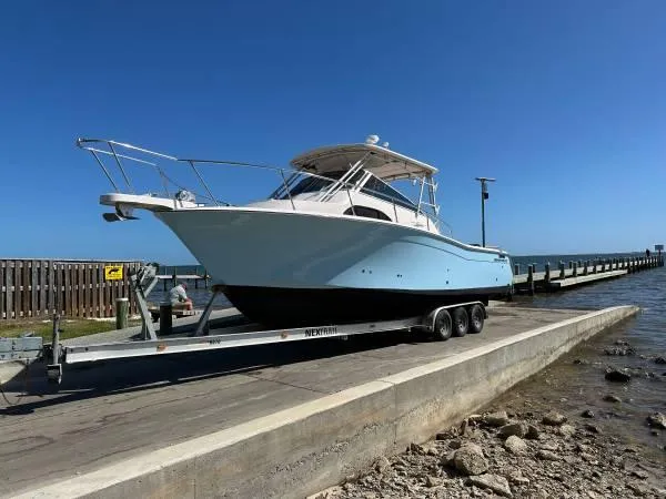 The Image of 2005 Grady-White Marlin 300 boat on trailer by the water, clear blue sky. - 1